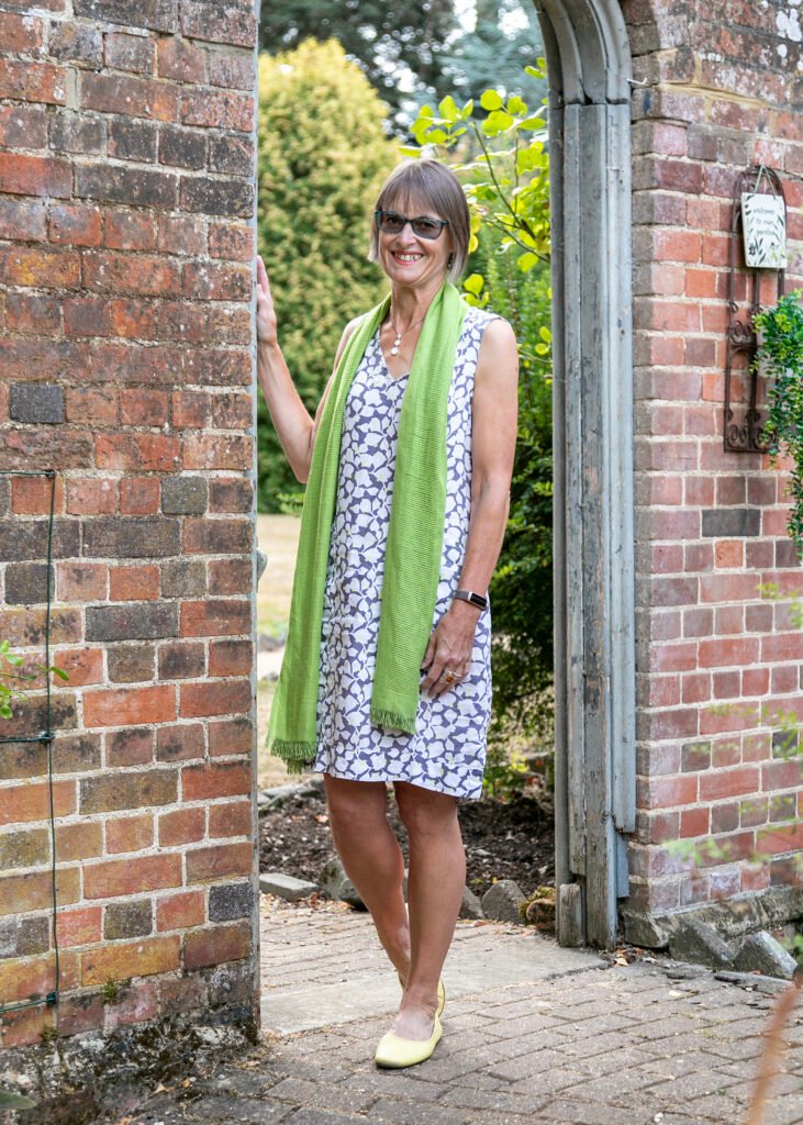 Linda standing in a doorway within a wall with her right hand resting against the brickwork
